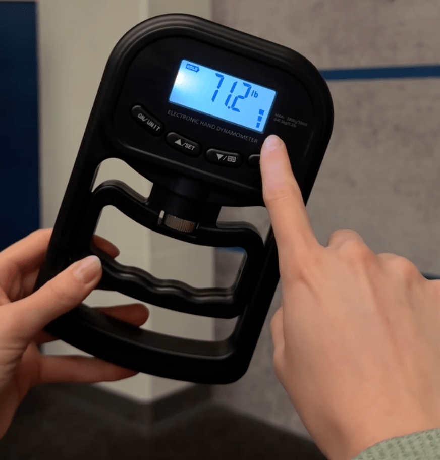 Digital hand dynamometer being used with a finger on the display